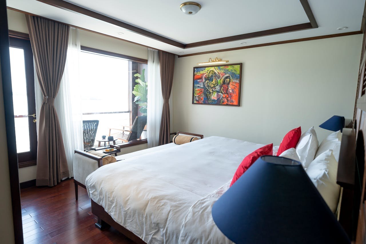 A luxurious bedroom with modern decor, large windows, and vibrant artwork.