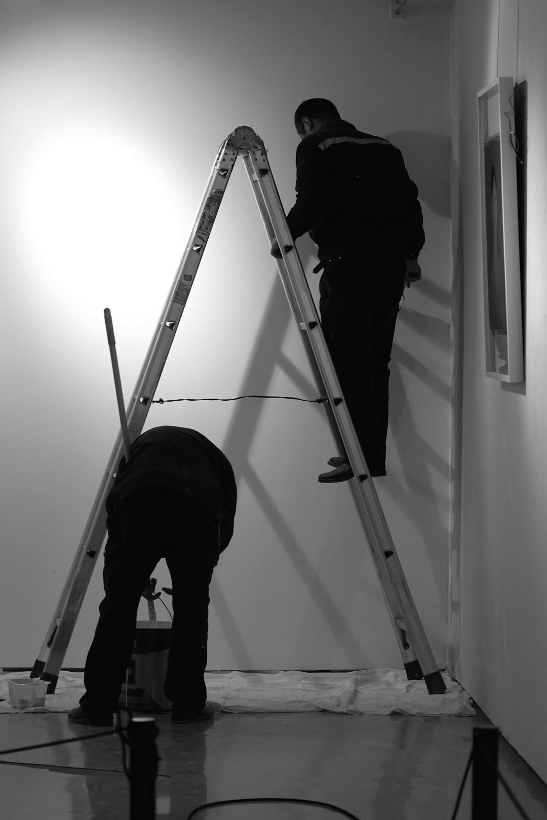 two-men-are-painting-a-wall-with-ladders-vrr-a-5jre0